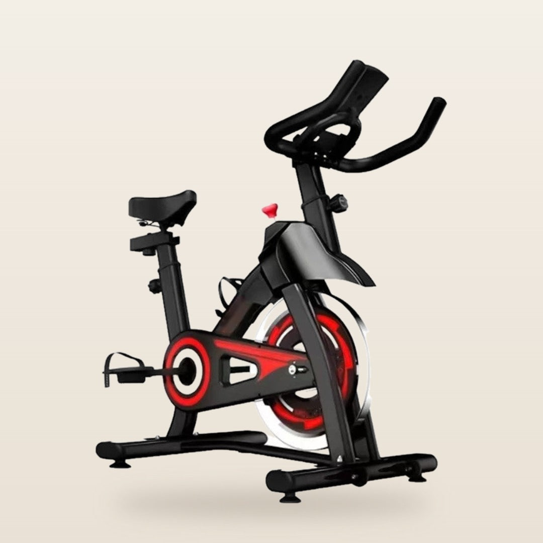 Bicicleta spinning com detalhes vermelhos, suporta até 150 kg, em fundo off-white